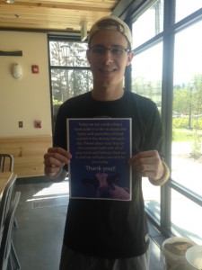 Chris Stefanik holds up a sign that he created pertaining to his work with food waste this summer