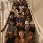 Group of SLL house members sit on a staircase smiling
