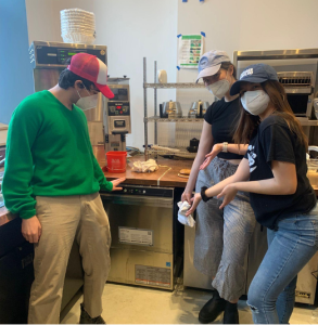 Three students in baseball caps pose in front of the new dishwasher