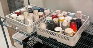 Two large dishwasher racks full of dirty mugs