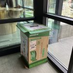 Green cardboard mask recycling box in the entry of the '66 Environmental Center