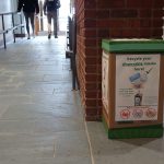 Mask recycling bin in front of brick wall