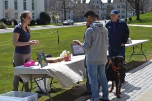 Couple with dog stands in front of an outdoor table with a sign that says Zilkha Center
