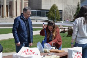Woman uses tool to make reusable bag while instructor looks on