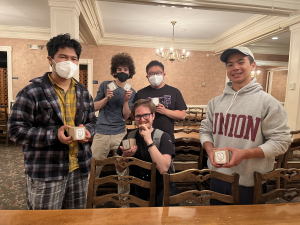 Five students hold small planters and smile