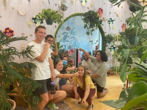 Interns stand pointing at plants in a vintage style shop