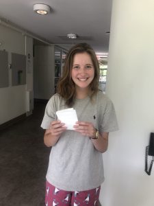 Student holding small white detergent sheets.