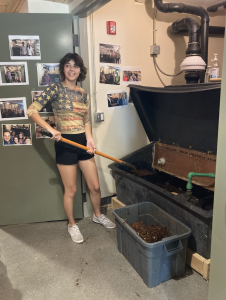 Student smiles while shoveling soil out of composting toilet system