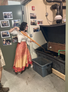 Student in skirt shovels compost out of composting toilet system