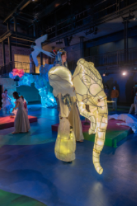 Performance set featuring a large, glowing elephant, soaring bird, and ice-like structure