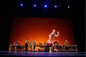 Person in red patterned dress dances in front of a live band