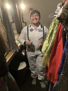 Student trying on an astronaut costume, with two thumbs up.