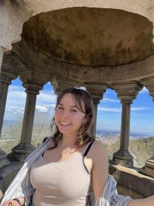 Woman in front of mountains, smiling. She has light brown hair.