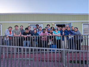 Large group of students stands smiling on a porch 