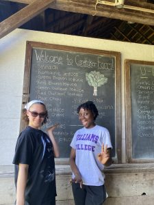 Two students standing in front of a sign of produce available at a local farm